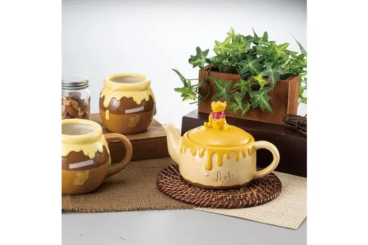 Winnie the Pooh teapot and tea mug placing on top of the placement and surrounded with plant