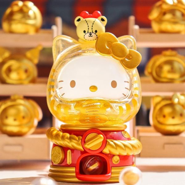 Hello Kitty Dharma Doll Gachapon figurine in gold with a cute bear topper, part of the Sanrio blind box collection