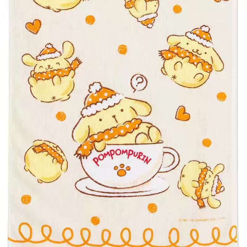 Close-up view of Pompompurin long towel detailing the adorable Pompompurin in a knitted cap, snugly sitting in a teacup surrounded by hearts, on a festive orange dotted background.