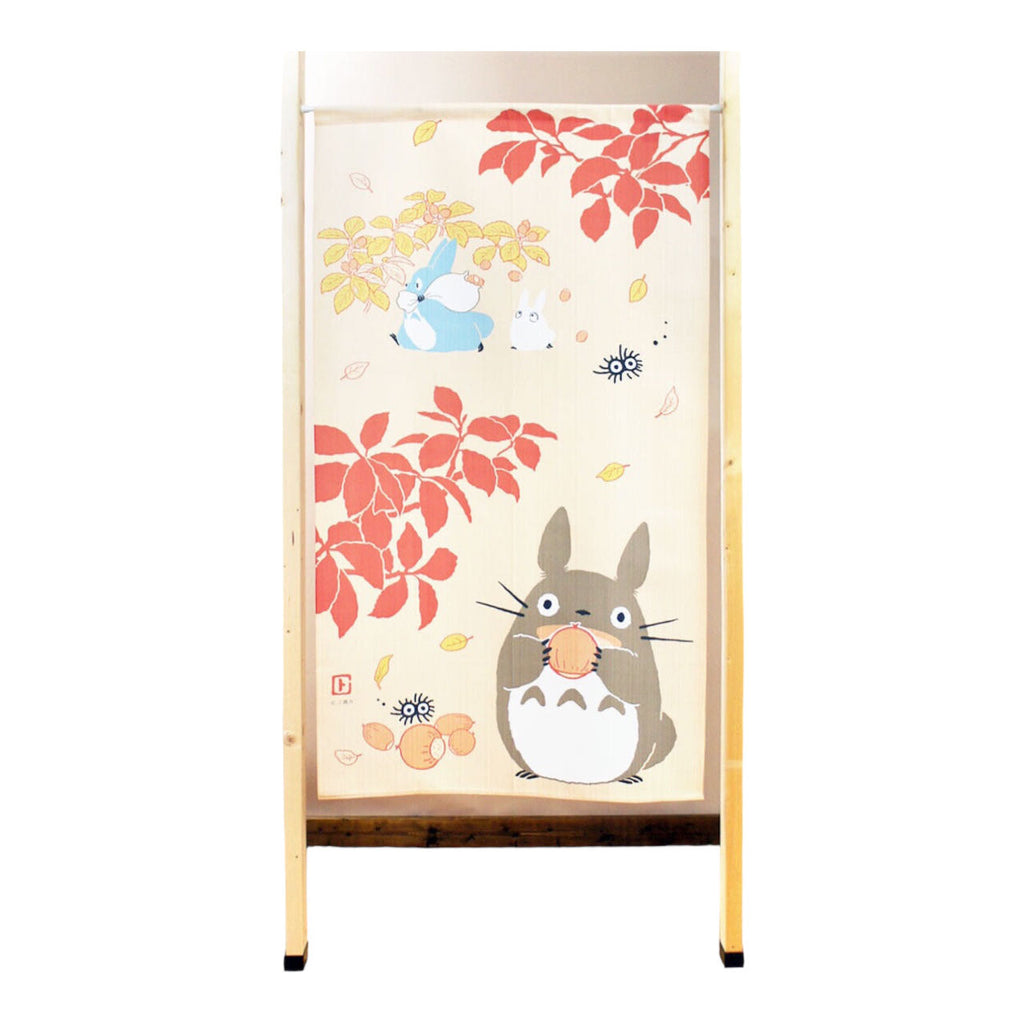 Cream-colored door curtain showcasing Totoro with an acorn, accompanied by smaller blue Totoro characters, spirited soot sprites, and vibrant red autumn leaves.