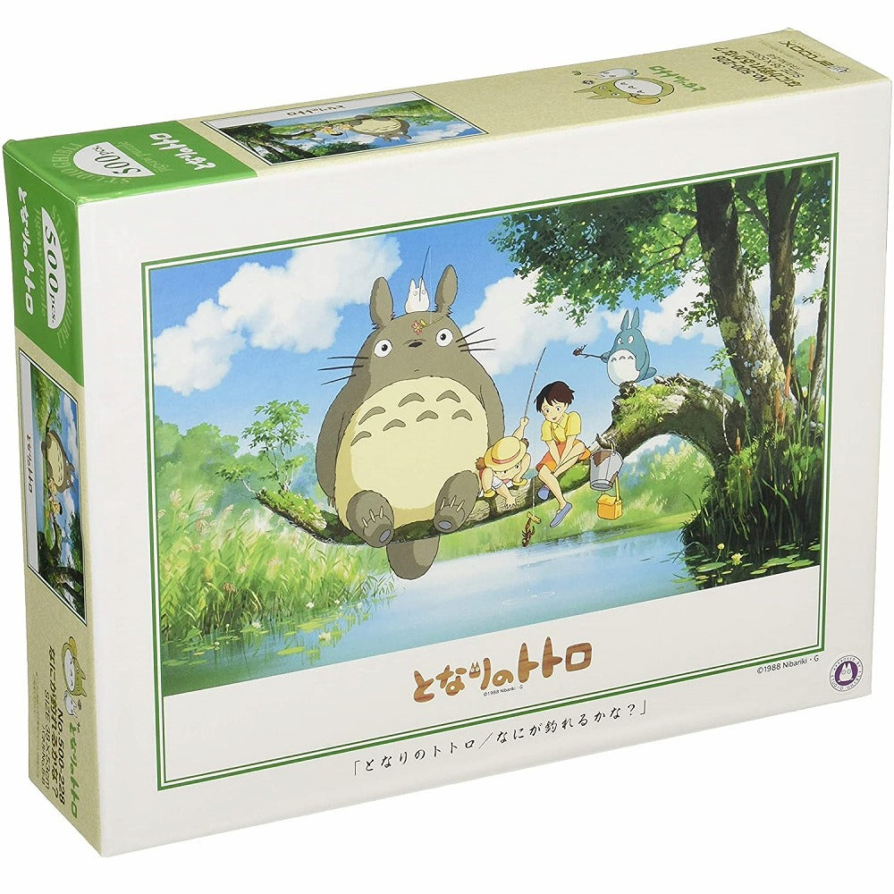 Box of My Neighbor Totoro 500-piece jigsaw puzzle showing Totoro, Satsuki, and Mei fishing on a tree branch over a pond under a bright blue sky.