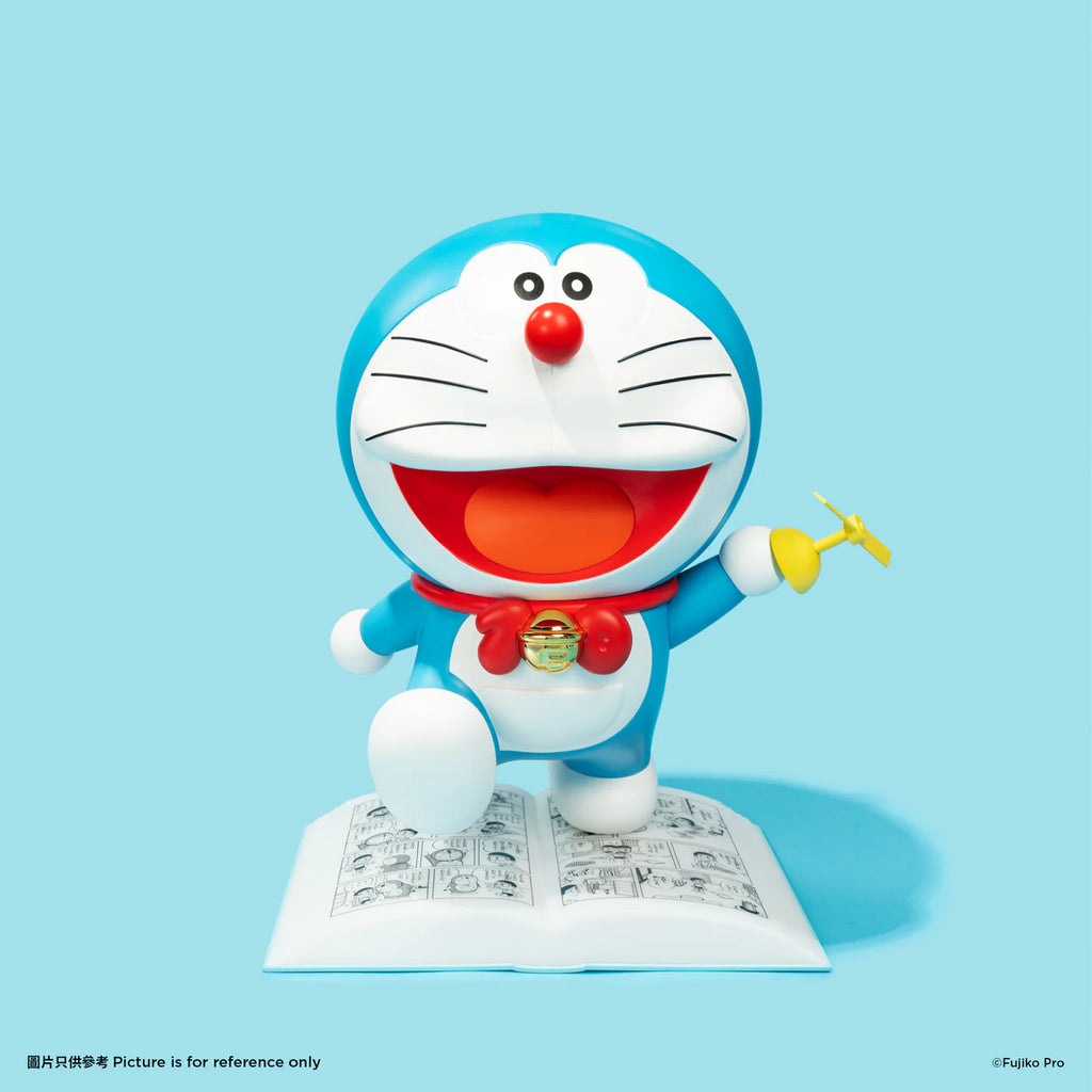 Doraemon night lamp with Doraemon holding a removable yellow propeller in his hand, standing on an open comic book, against a blue background.