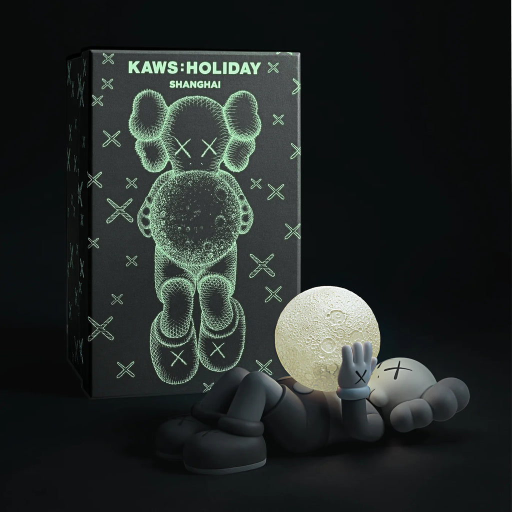 KAWS SHANGHAI Grey figure displayed alongside its packaging featuring a glow-in-the-dark design.