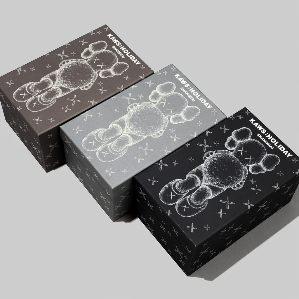 Three packaging boxes for KAWS
SHANGHAI figure, with glow-in-the-dark designs showcasing the Companion holding a moon in different color variations.