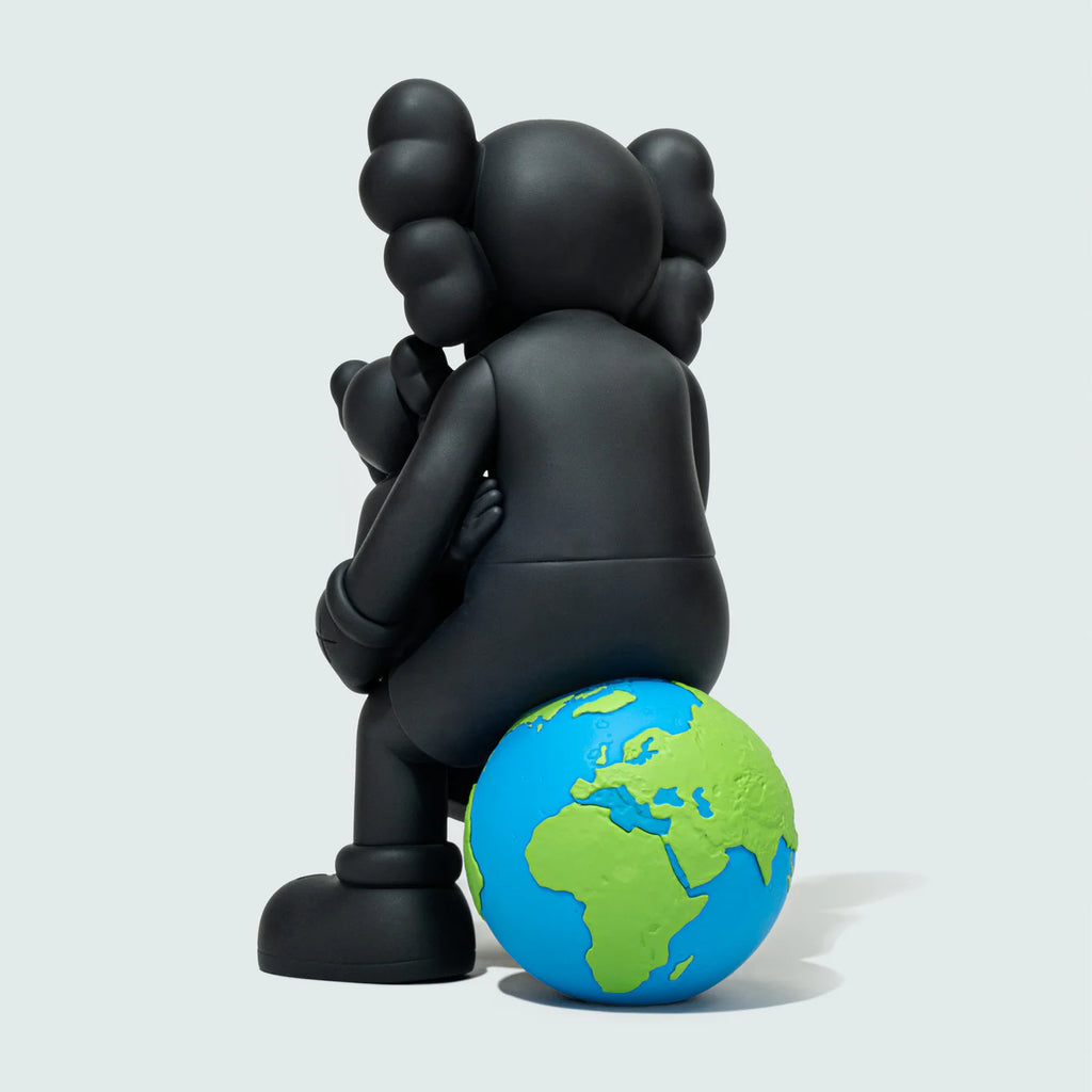 Back view of KAWS black collectible figure sitting on a globe