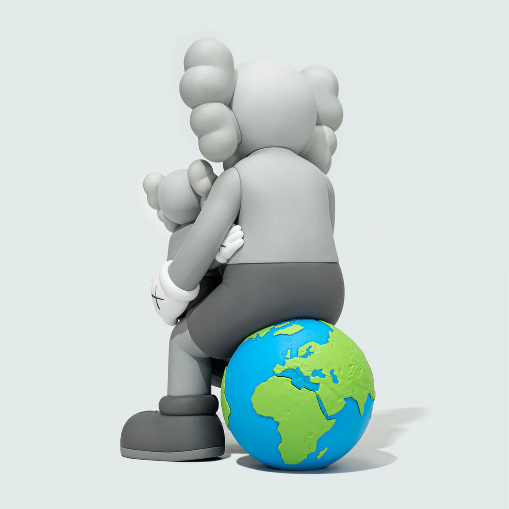 Rear view of KAWS:HOLIDAY THAILAND Grey figure seated on Earth globe, child figure resting against the adult Companion.