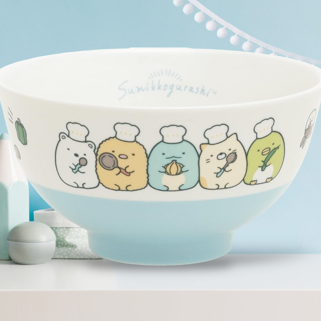 Close-up of San-X Sumikkogurashi blue ceramic rice bowl with colorful character designs including a polar bear, penguin, and cat.