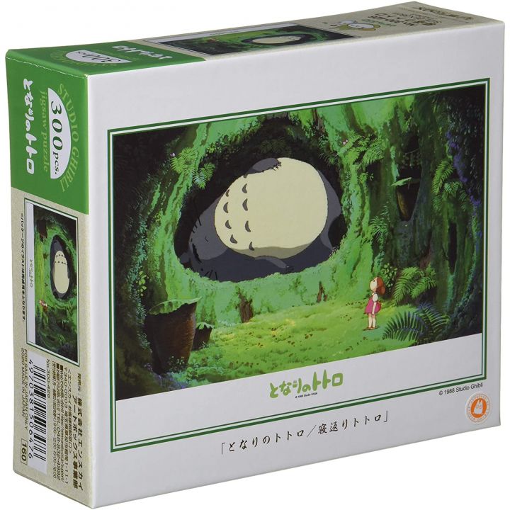 Box of My Neighbor Totoro 300-piece jigsaw puzzle depicting Totoro resting inside a forest hollow, with Mei watching curiously.