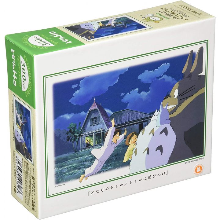 Box of Studio Ghibli 300-piece jigsaw puzzle featuring Satsuki and Mei joyfully jumping onto Totoro at night, with their house in the background.