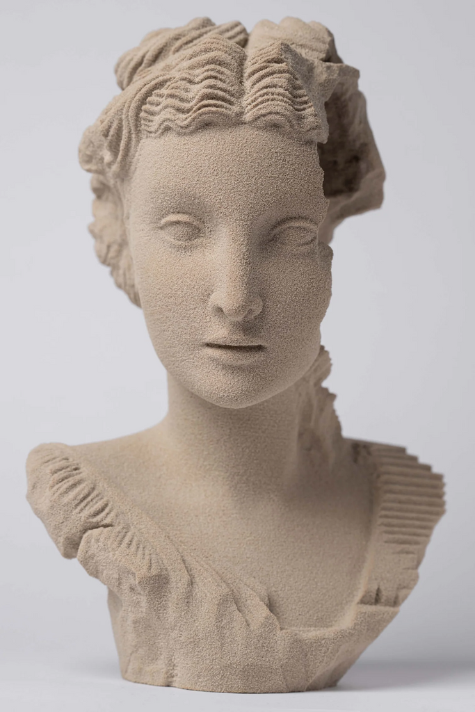 Frontal view of the sculpture showing detailed facial features and sand texture