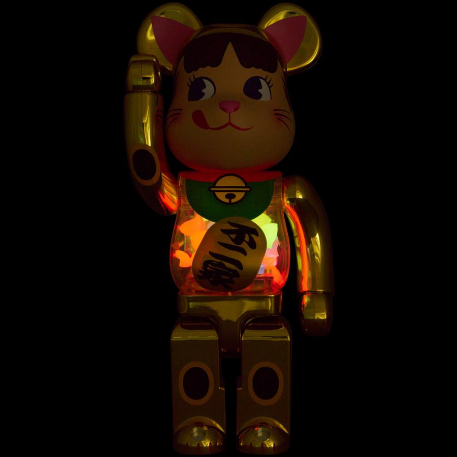 Bearbrick Maneki Neko Peko-Chan Gold Ver. glowing in the dark, highlighting its LED-lit body.