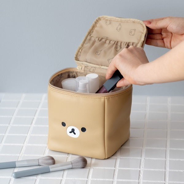 Hand opening the Rilakkuma makeup pouch revealing a spacious compartment for cosmetics and tools.