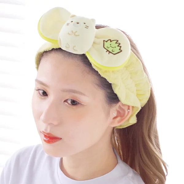 Model wearing the Sumikkogurashi Neko hair band during a skincare routine, showcasing the plush cat design and soft material.