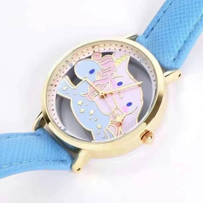 Sanrio Cinnamoroll wristwatch lying flat, with a light blue textured strap and a gold-rimmed face featuring a unicorn motif