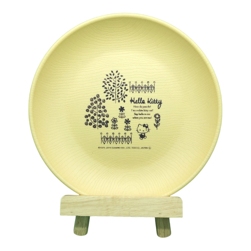 Pale yellow Sanrio Hello Kitty plate with intricate floral and Hello Kitty illustrations, displayed on a wooden stand.