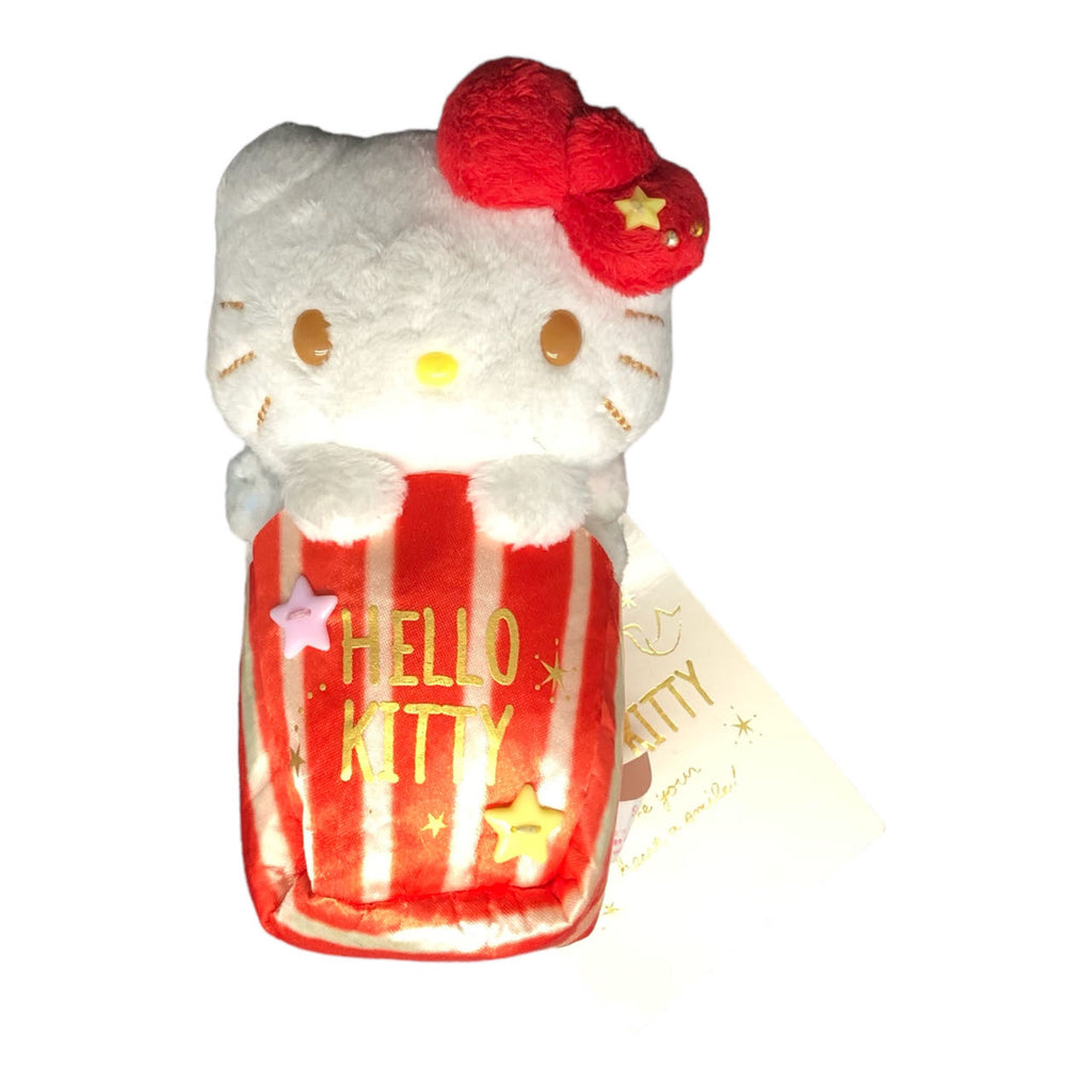 Hello Kitty plush toy peeking out of a red and white striped popcorn box, adorned with stars and the 'Hello Kitty' logo, complete with her iconic red bow.