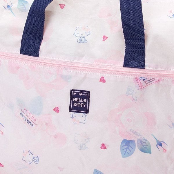 Close-up of the Hello Kitty travel duffel bag's fabric showing delicate pink roses and Hello Kitty illustrations with travel stamps