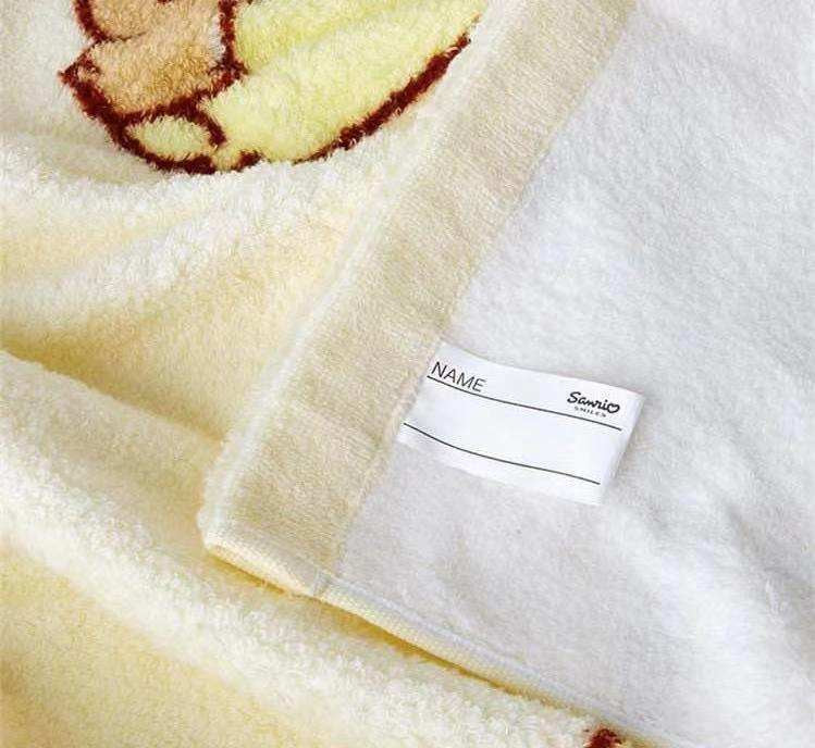 Label detail on Pompompurin square facial towel showing the Sanrio brand name.