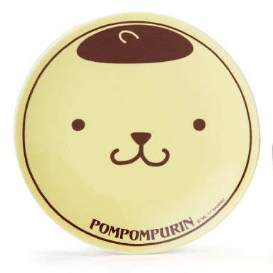 Close-up view of the Pompompurin coffee saucer with a cute illustration of Pompompurin's face on a pale yellow background.