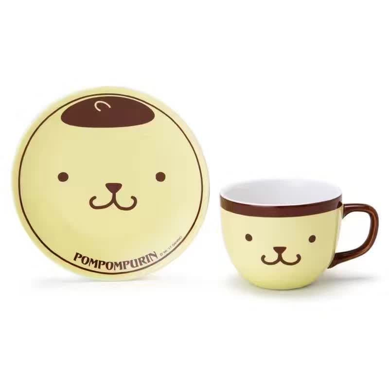 Pompompurin coffee mug and saucer set displayed, featuring the adorable dog's face on a yellow background with a brown rim.