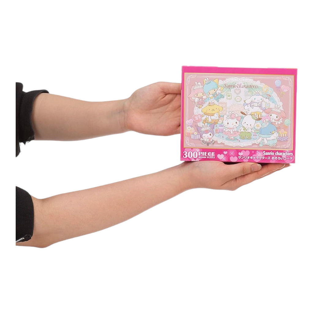 Hands holding a compact box of Sanrio Characters 300-piece puzzle, showcasing the puzzle's pastel wonderland artwork on the cover.