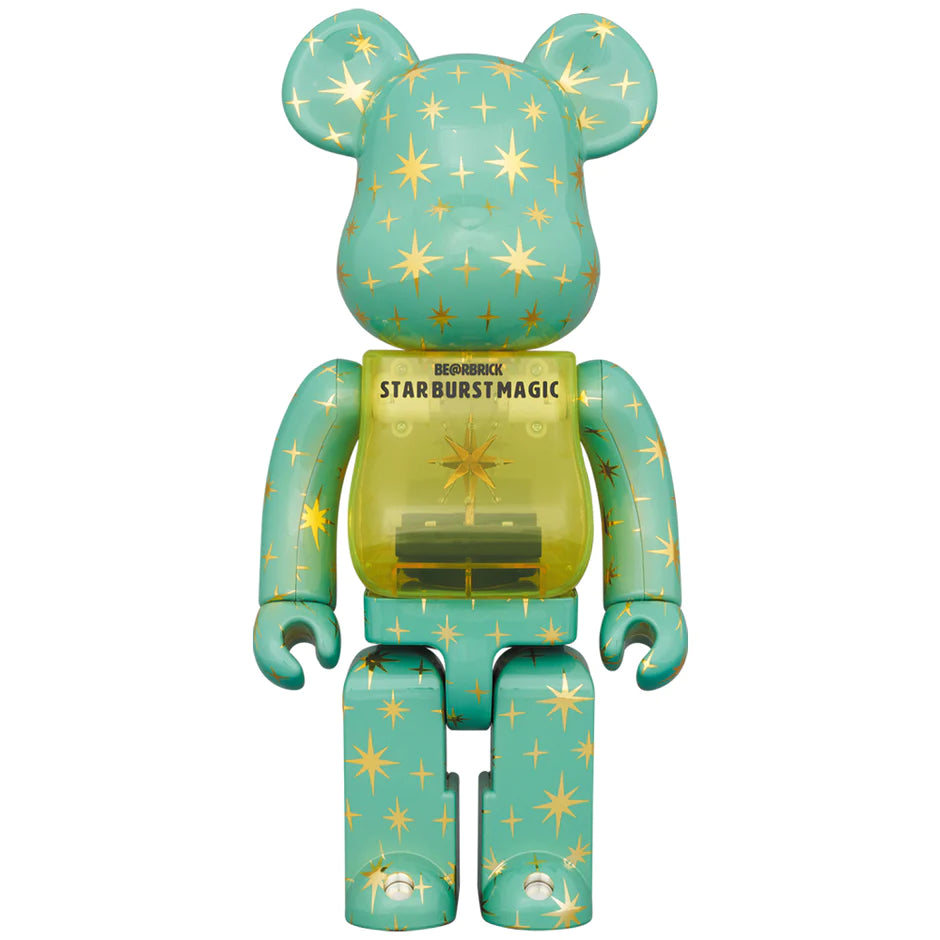 The Bearbrick 400% Star Burst Magic figure stands tall with a starry design against a turquoise backdrop, boasting a transparent chest showing an inner mechanical structure.