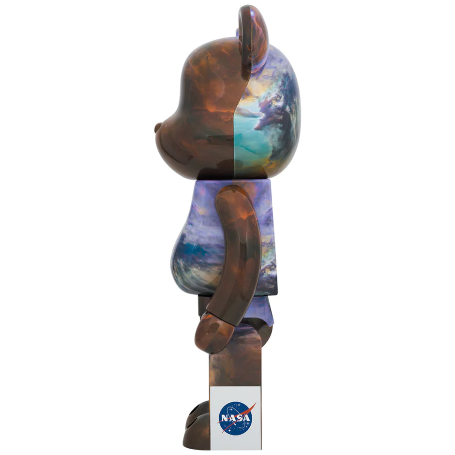 side view of Bearbrick figures in 100% and 400% sizes, adorned with the vibrant Lagoon Nebula image from the Hubble Space Telescope
