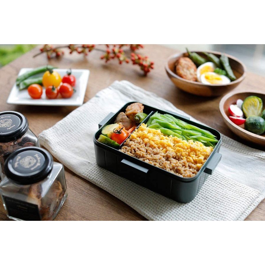 A chic black lunch box filled with a well-organized meal, demonstrating an alternative design for sophisticated tastes.